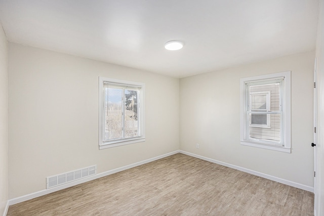 spare room featuring visible vents, baseboards, and light wood-style floors