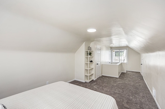 bedroom featuring lofted ceiling, baseboards, visible vents, and dark carpet