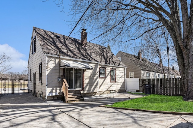 cape cod home with fence, entry steps, a front yard, a chimney, and a gate