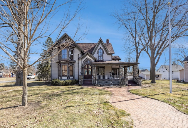 view of front of house with a front yard, a porch, a chimney, and roof with shingles