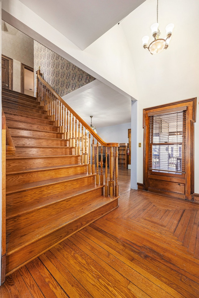 foyer entrance with parquet floors, stairs, and an inviting chandelier