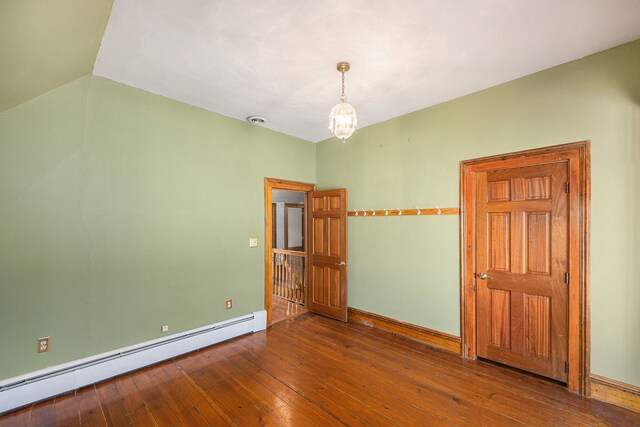 spare room with a baseboard heating unit, an inviting chandelier, hardwood / wood-style floors, and vaulted ceiling