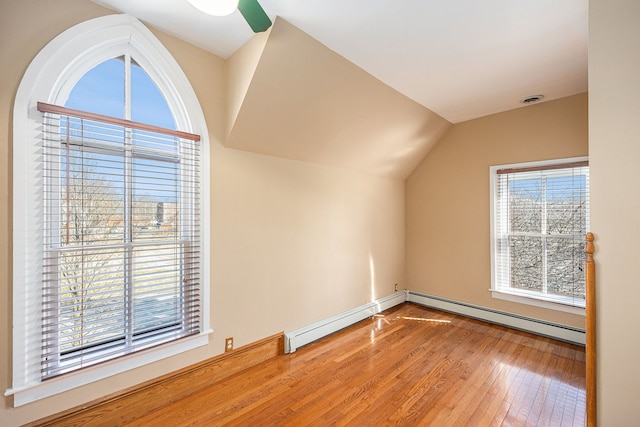 additional living space with baseboard heating, lofted ceiling, and hardwood / wood-style floors