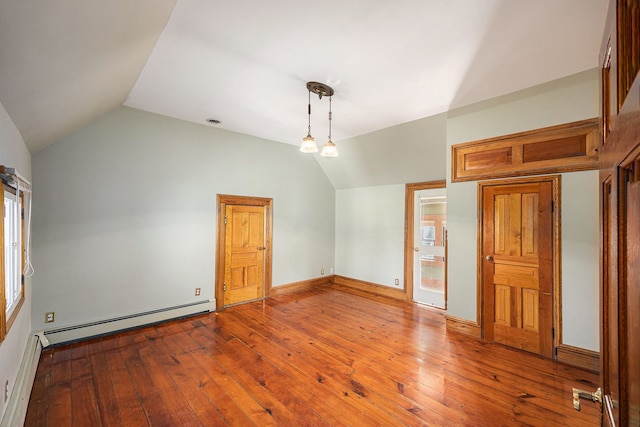 spare room with a baseboard radiator, baseboard heating, hardwood / wood-style floors, and vaulted ceiling