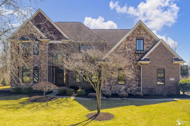 view of front of property featuring stone siding, brick siding, a front lawn, and a shingled roof