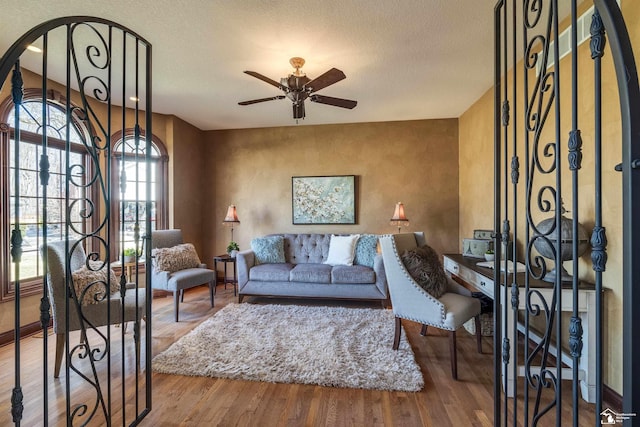 living area with a textured ceiling, a ceiling fan, and wood finished floors