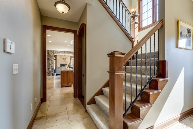 stairs with arched walkways, tile patterned floors, and baseboards