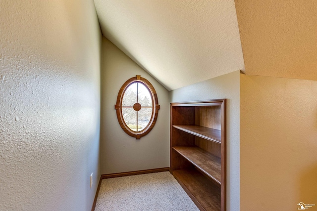 interior space featuring a textured ceiling, baseboards, carpet, and a textured wall