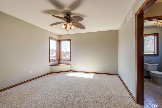 carpeted spare room featuring tile patterned floors, visible vents, baseboards, and a ceiling fan