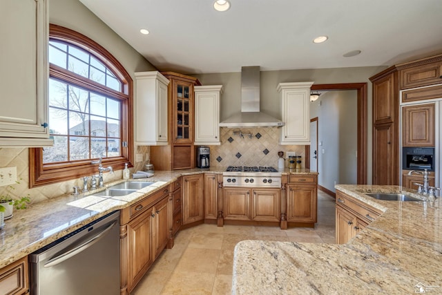 kitchen with light stone countertops, appliances with stainless steel finishes, and wall chimney exhaust hood