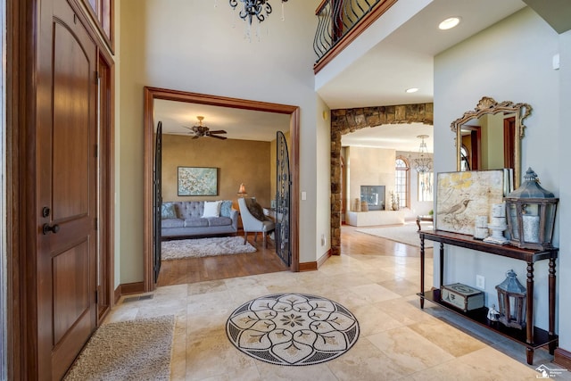 entryway featuring baseboards, arched walkways, and ceiling fan with notable chandelier