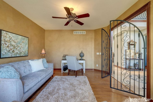 living area featuring visible vents, baseboards, ceiling fan, and wood finished floors