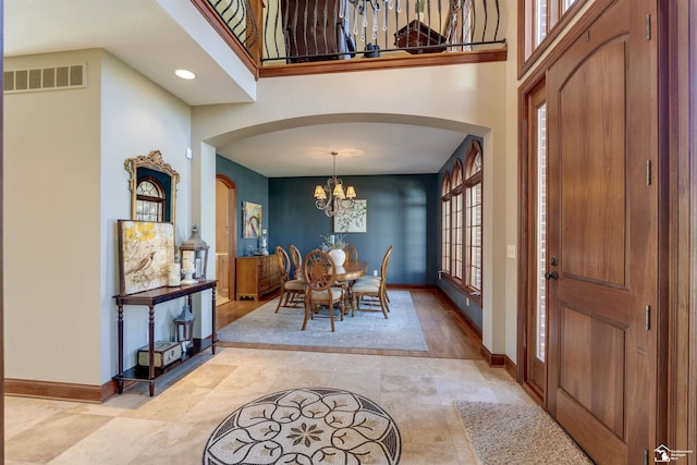 entrance foyer with arched walkways, visible vents, a chandelier, and baseboards