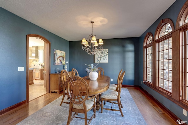 dining space featuring arched walkways, light wood-type flooring, and a wealth of natural light