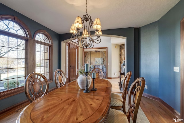 dining room with wood finished floors, baseboards, visible vents, arched walkways, and a chandelier