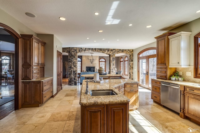 kitchen with arched walkways, dishwasher, ornate columns, and a sink