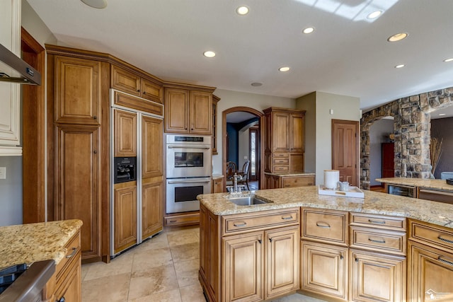 kitchen featuring a sink, paneled refrigerator, arched walkways, and double oven