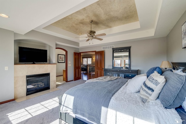 bedroom featuring a tray ceiling, light carpet, and visible vents