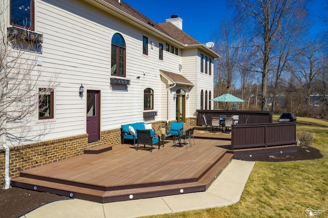 back of house with a chimney, a deck, and outdoor dining space