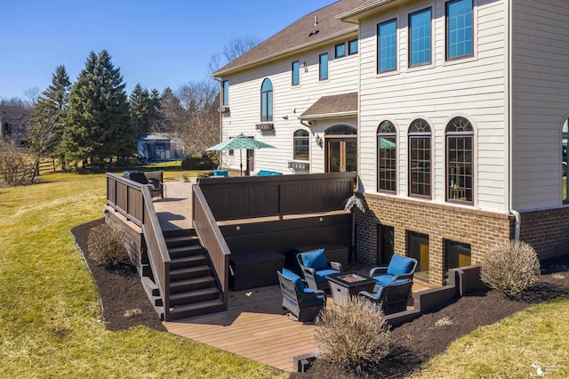 rear view of property featuring a deck, an outdoor fire pit, a yard, brick siding, and stairs