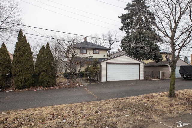 view of front facade featuring a garage, an outbuilding, and fence