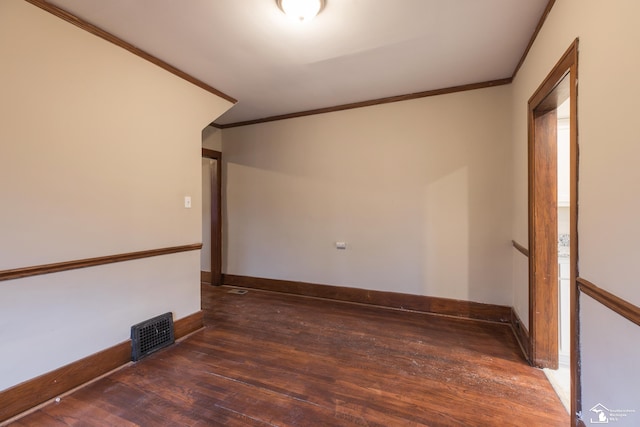 unfurnished room with visible vents, crown molding, baseboards, and wood finished floors