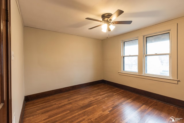 unfurnished room featuring dark wood finished floors, a ceiling fan, and baseboards