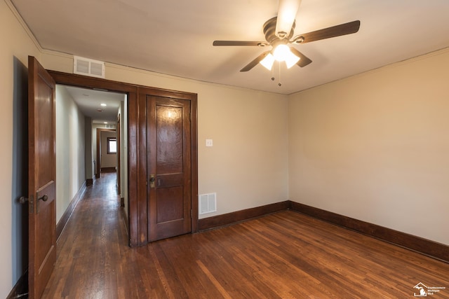 empty room featuring baseboards, visible vents, dark wood-style flooring, and ceiling fan