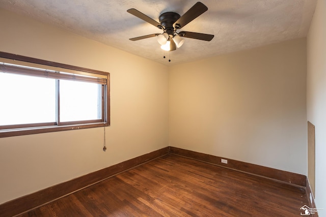 unfurnished room featuring a textured ceiling, dark wood-type flooring, baseboards, and a ceiling fan