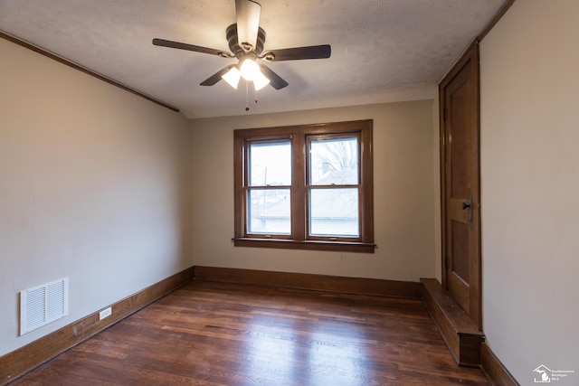 spare room with visible vents, baseboards, ceiling fan, dark wood finished floors, and a textured ceiling