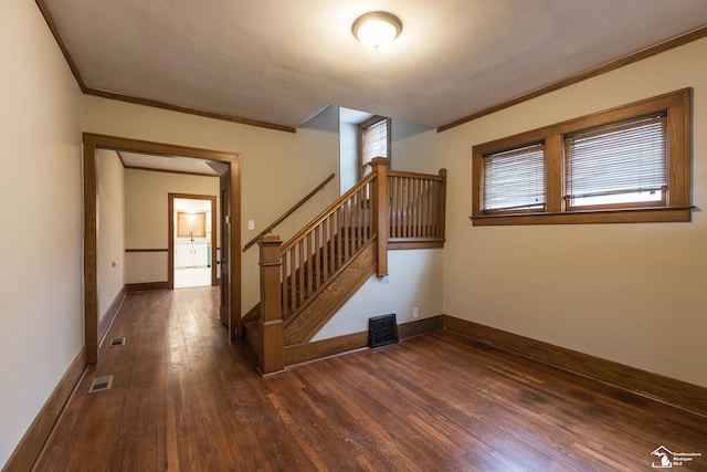 staircase featuring visible vents, baseboards, ornamental molding, and hardwood / wood-style flooring