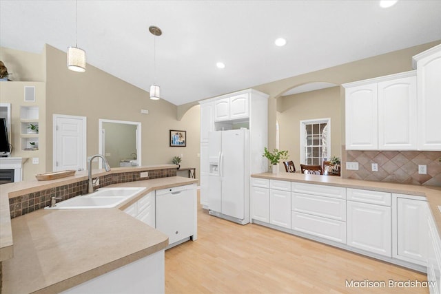 kitchen featuring pendant lighting, a sink, white appliances, arched walkways, and light countertops