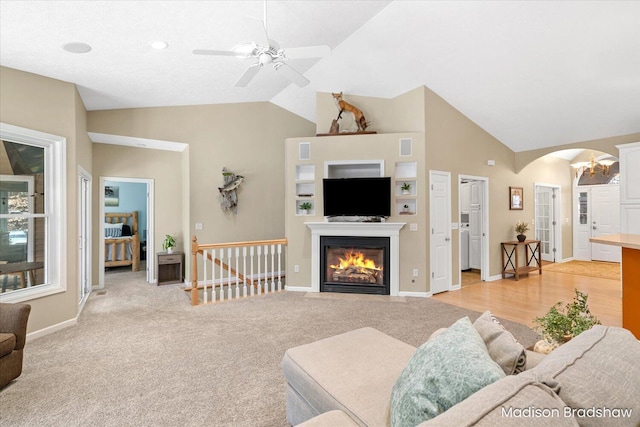 living room featuring arched walkways, lofted ceiling, ceiling fan, and a fireplace with flush hearth