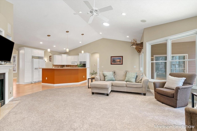 living area with a fireplace with flush hearth, high vaulted ceiling, light carpet, a ceiling fan, and recessed lighting