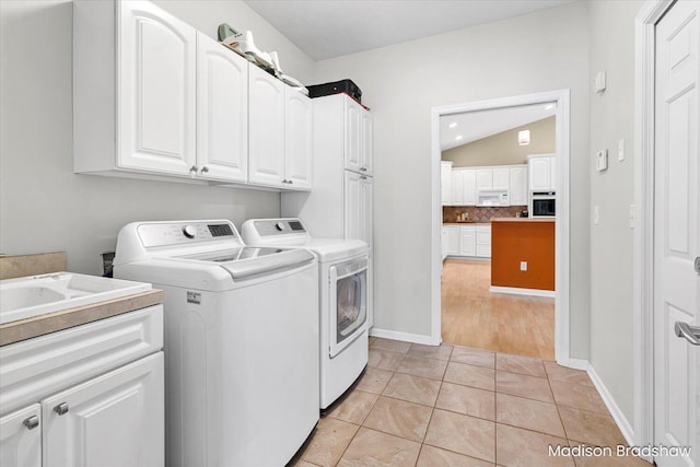 laundry room featuring baseboards, cabinet space, washing machine and dryer, and light tile patterned flooring