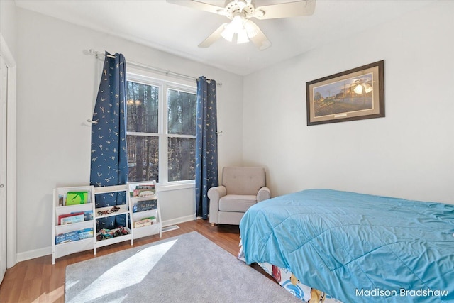 bedroom with multiple windows, wood finished floors, and baseboards