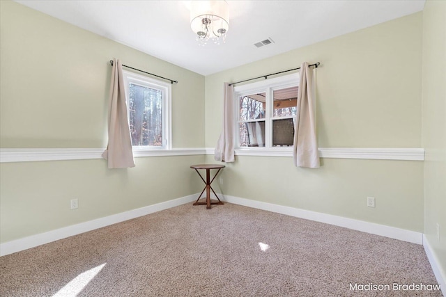 carpeted spare room with visible vents and baseboards