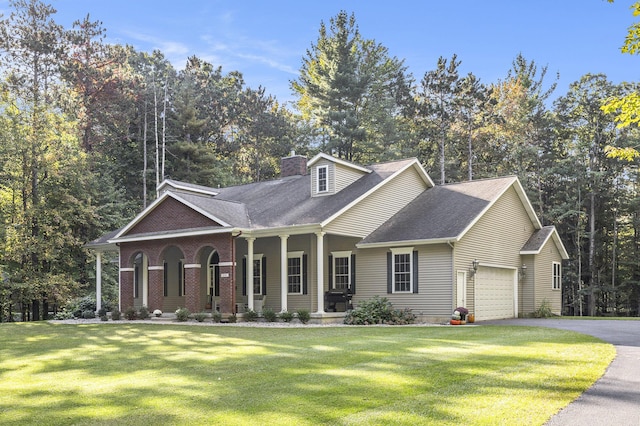 view of front of home with driveway, covered porch, a chimney, a front lawn, and a garage