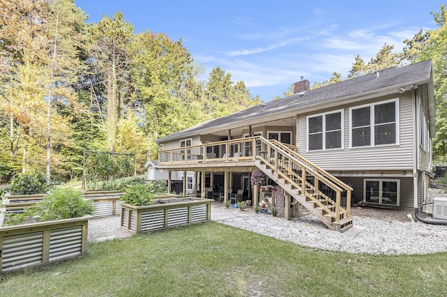 back of house featuring stairway, a lawn, a chimney, a garden, and a patio