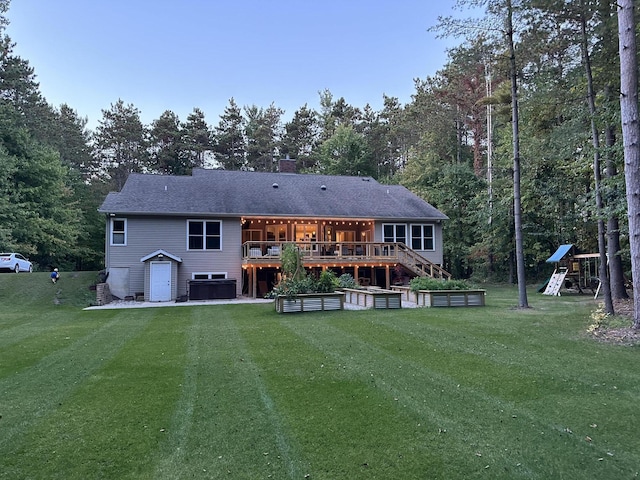 rear view of property featuring central air condition unit, a lawn, a deck, and a playground