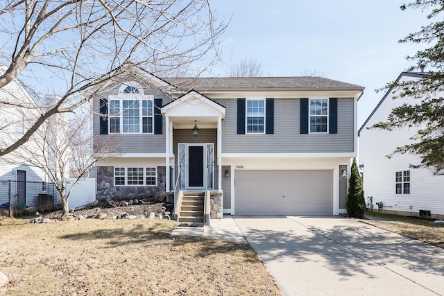 bi-level home featuring stone siding, driveway, and an attached garage