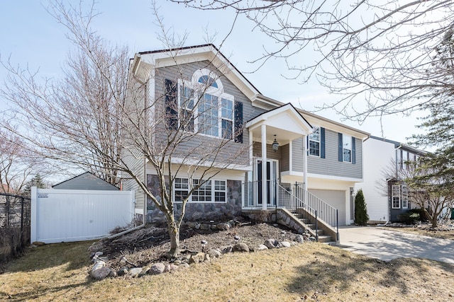 view of front of house with concrete driveway, an attached garage, and fence