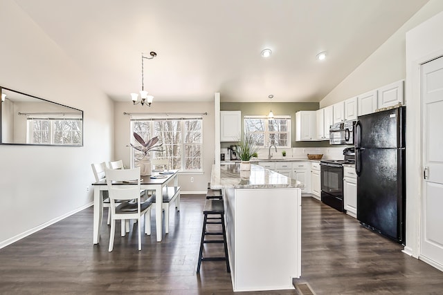 kitchen with a notable chandelier, black appliances, a sink, white cabinetry, and lofted ceiling