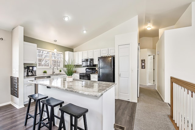 kitchen with visible vents, black appliances, a breakfast bar, white cabinets, and lofted ceiling