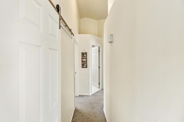 hall with a barn door, carpet floors, and vaulted ceiling