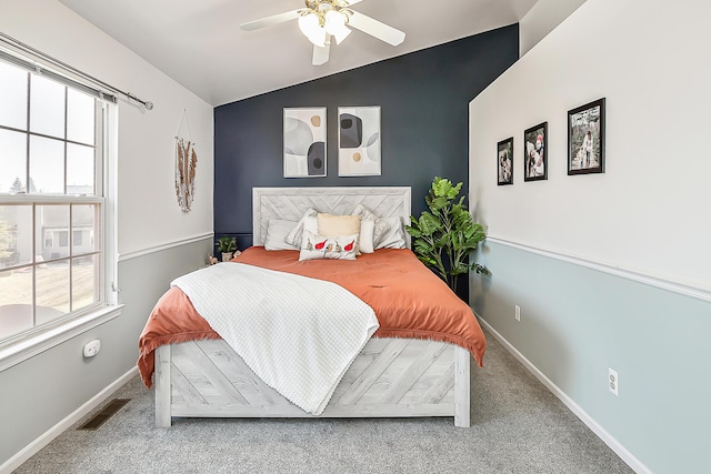 carpeted bedroom with vaulted ceiling, multiple windows, baseboards, and visible vents