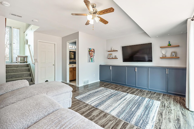 living area with stairs, wood finished floors, visible vents, and ceiling fan