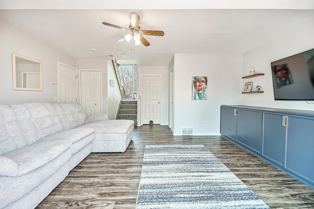 living room with baseboards, visible vents, ceiling fan, stairs, and dark wood-type flooring