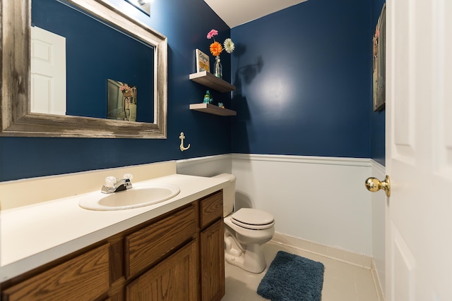 half bath featuring toilet, vanity, and tile patterned flooring