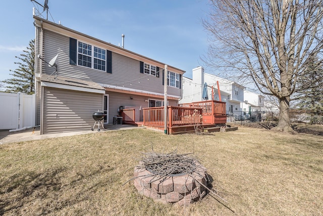 back of property featuring a deck, fence, and a lawn